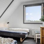 Schlafzimmer mit Dachschräge, Fenster und Bett.