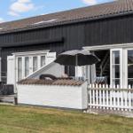 Schwarzes Holzhaus mit weißem Balkon und Gartenbereich unter Sonnenschirm.