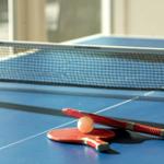 Tischtennisplatte mit Schlägern und Ball. Spielbereich im Innenbereich.