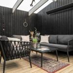 Terrasse mit Sofa, Sitzgelegenheit und Holzboden. Schwarze Wände und Holzrahmen.