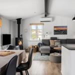 Wohnbereich mit Sofa, Kamin und Esstisch. Weiße Wände und Holzboden.