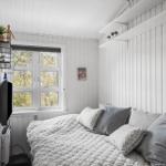 Schlafzimmer mit Bett, Fenster und Wandregalen.