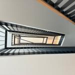 Moderne Treppe mit schwarzem Metallgeländer und Holzhandlauf.