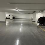 Untergeschoss-Parkhaus mit zwei geparkten Fahrzeugen und gelben Markierungen.