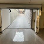 Garage mit Rolltor und Blick auf eine Straße mit Backsteinmauer