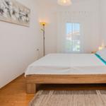 A bedroom with wooden bed, white walls, and window with curtains.