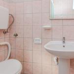 Bathroom with toilet, sink, and mirror on pink tiles.