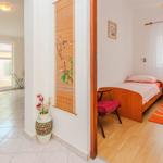 Bedroom with wooden bed and nightstand. View into dining area with table and chairs.