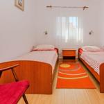 Two single beds, a nightstand, a window with curtains, and a red armchair.