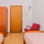 Two beds with orange pattern, wardrobe, door, and red seating.