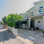 Green house with stone entrance and balcony, paved yard, sea view.