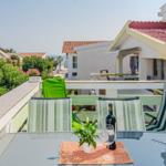 Terrace with table, chairs, and sea view. Wine bottle and plant on table.