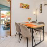 Dining area with table and chairs, view into living room with balcony.