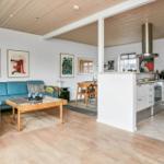 Wohn- und Küchenbereich mit Holzboden, blauem Sofa und moderner Küche.