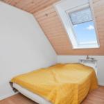 Schlafzimmer mit Dachschrägen, gelbem Bett und Dachfenster.