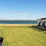 Grüner Rasenbereich mit Blick auf Wasser und Ferienhäuser.