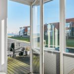 Terrasse mit Sitzgelegenheit und Blick auf Wohnhäuser und Wasser.