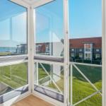 Durch große Fenster mit Blick auf Grünfläche und Häuser.