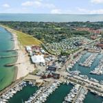 Hafen mit Booten, Strand und Ferienpark in der Ferne.