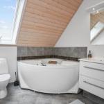 Badezimmer mit Dachfenster, Badewanne, Waschbecken und Toilette.