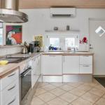 Küche mit weißen Schränken, Holzoberflächen und Edelstahlgeräten.