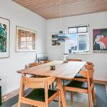 Esszimmer mit Holztisch, Stühlen und Wandbildern. Decke aus Holz.