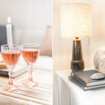 Zwei Gläser Rosé auf einem Tisch mit Kerzen. Lampe, Bücher und Muschel auf einem Nachttisch.