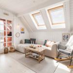 Wohnzimmer mit Sofa, Schaukelstuhl und Dachfenstern. Holzboden und weiße Wände.