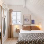 Schlafzimmer mit Bett, Fenster und Wandbildern.