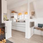 Küche mit Essbereich und Kaminofen. Weiße Einbauküche und Sitzbank mit Felldecke.