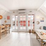 Wohn- und Essbereich mit weißen Wänden, Holzboden und französischen Türen.