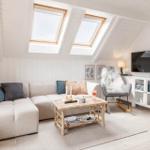 Wohnzimmer mit Sofa, Couchtisch und Fernseher unter Dachfenstern.