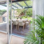 Glas-Tür führt auf Terrasse mit Tisch und Stühlen.