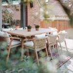 Terrasse mit Holztisch und Stühlen, Pflanzen und Blick auf Haus.