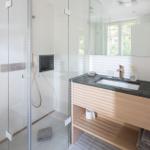 Bad mit Dusche, Waschbecken und Toilette. Moderne Einrichtung mit Glaswand.