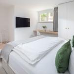 Schlafzimmer mit Bett, Schreibtisch und TV. Fenster mit Blick nach draußen.