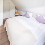 Schlafzimmer mit Doppelbett, Holzboden und schräger Decke.