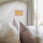 Schlafzimmer mit Bett, Wanddekoration und Fenster mit Blick auf Außenbereich.