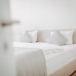 Ein Bett mit weißen Kissen und Bettwäsche im Schlafzimmer.