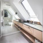 Badezimmer mit Dachschrägen, Waschbecken und Glaswand-Dusche.