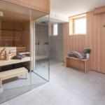 Dusche und Sauna in einem Raum mit Holzwänden und Bodenfliesen.