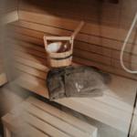 Sauna mit Holzbank, Eimer und Handtuch.