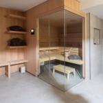 Sauna mit Glaswand, Dusche und Holzbank im Badezimmer.