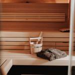 Sauna mit Holzbank, Eimer und Handtuch.