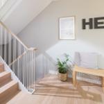 Treppenhaus mit Holzstufen, Sitzbank und Pflanze an der Wand.