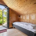 Schlafzimmer mit Bett, Holzwand und Terrassentür.