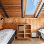 Zwei Betten unter Holzdach mit Dachfenster und Regal.