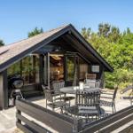 Haus mit Terrasse, Grill und Sitzgelegenheiten. Holzhaus mit Schiebetüren und Satellitenschüssel.