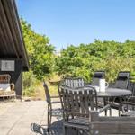 Terrasse mit Tisch, Stühlen und Blick auf grüne Vegetation.