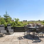 Terrasse mit Liegestühlen und Tisch für sechs Personen. Blick auf grüne Landschaft und Ferienhaus.
